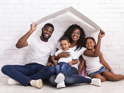 Family Housing Concept. Young African American Parents With Two Children Sitting Under Car