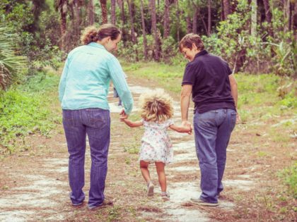 Lesbian couple and their little girl on a walk in a nature area